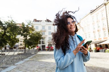Neşeli, kıvırcık saçlı, güneş gözlüğü takan gezgin kadın...