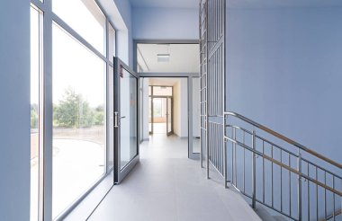 Merdiveni olan koridor. Dışarıya bakan koridorları olan büyük, parlak odalar..