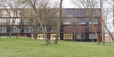 Şehirde modern bir bina. Korsajdan yapılmış ön cephe. Paslı metal levha. Büyük pencereler. Polonya