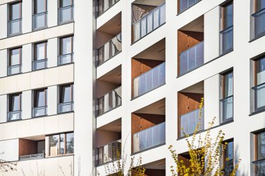 Şehir merkezindeki çoklu aile binasının detayları. Çok sayıda kat var. Balkonlar ve loggialar. Binanın etrafında büyük miktarda yeşillik var.