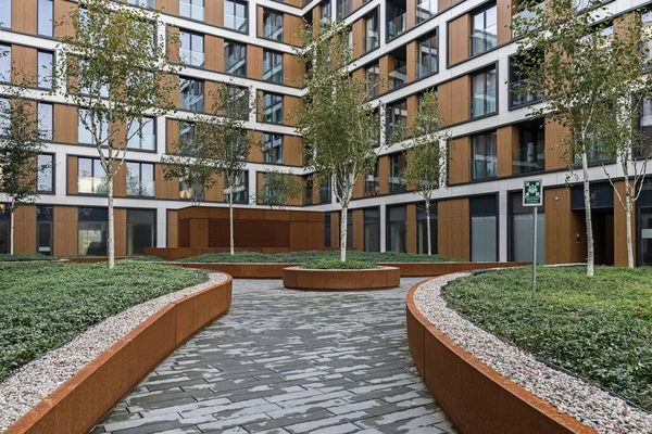Residential buildings in a European city. Modern blocks of flats. Courtyard with vegetation and lighting. Rust metal finish, corten. Underground garage