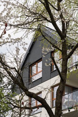 Avrupa 'da modern bir çoklu aile binasında ön cephe ve balkonların ayrıntıları. İlginç bir mimari. Bitkilerin ve ağaçların arasında. Çiçek açan bahar