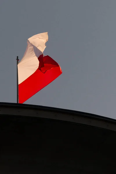 Polish flag in strong wind. A national holiday in Poland. A labor holiday.  May Day weekend. Poland's Independence Day. The white and red flag on a flagpole.