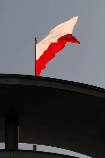 Polish flag in strong wind. A national holiday in Poland. A labor holiday.  May Day weekend. Poland\'s Independence Day. The white and red flag on a flagpole.