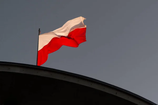 Polish flag in strong wind. A national holiday in Poland. A labor holiday.  May Day weekend. Poland's Independence Day. The white and red flag on a flagpole.