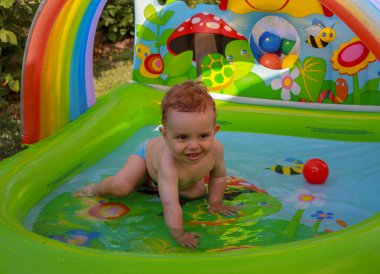 Bebek yazın plastik havuzda eğleniyor.