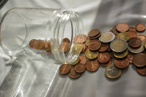 the euro coins out of the glass jar to pay invoices