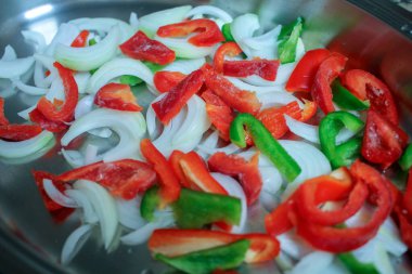 sliced onion and red and green pepper are ready to be cooked