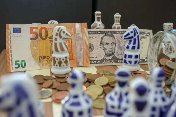 euro and dollar notes and euro cash on the chessboard