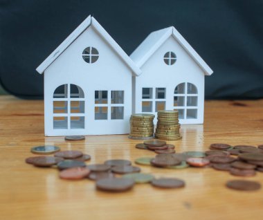 euro coins on the table and tiny white houses to buy