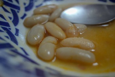 Lezzetli fasulyeler ve bir kaşık dolusu yemek.