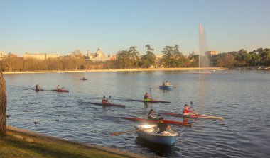 Madrid 'deki Casa de Campo gölünde gün batımında kürek çeken insanlar