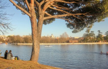 Madrid 'deki Casa de Campo gölünde gün batımında kürek çeken insanlar