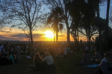 people in a park in Madrid enjoying sunset lights spreading along the city clipart