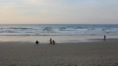 Günbatımında Aguilar sahilinde yürüyen insanlar