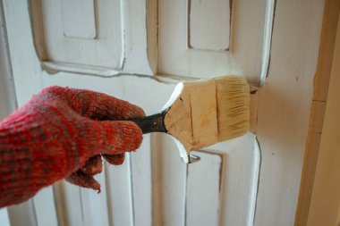 Bir kapıyı beyaza boyamak için eldiven giyiyor.