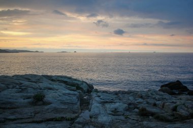 İspanya, Burela 'daki Cantabrian kıyılarındaki kayalıklarda gün batımı ışıkları