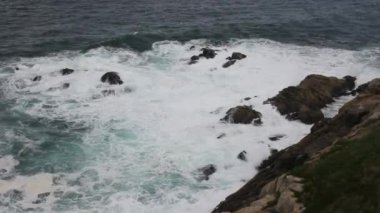 Cantabrian Denizi 'nde kayaların yanında dalgalar ve köpük var.