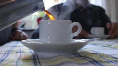 Yaşlı bir çift evde bir fincan sıcak kahve içiyor.