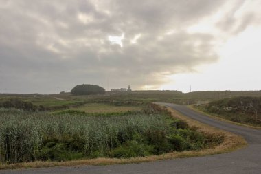 road under cloudy sky in Estaca de Bares, Spain clipart