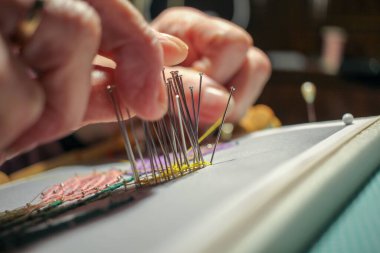 Evde iplikle çiçek yapan yaşlı bir kadın.