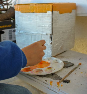 Bir genç, kartondan bir ev yapıyor.