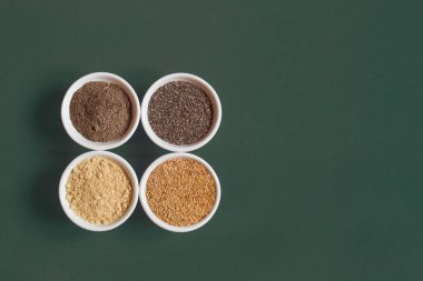 Chia and flax seeds both ground and whole on white ceramic bowls on a colorful studio background with copy space. Healthy Seeds to Eat.