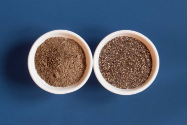Top view of a close-up of two ceramic bowls side by side with whole and powdered chia. Healthy Seeds to Eat.