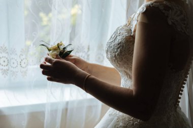 Pencere önünde çiçek tutan bir gelin.