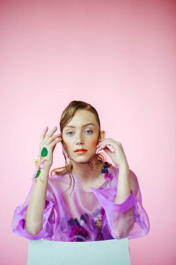 Güzel bir kız, şeffaf mor bir bluz ve zarif bir saç modeli olan taze çiçeklerle sütyen giyiyor.