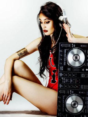 Uzun siyah saçlı, kulaklıklı ve müzik kontrolörlü güzel bir DJ.
