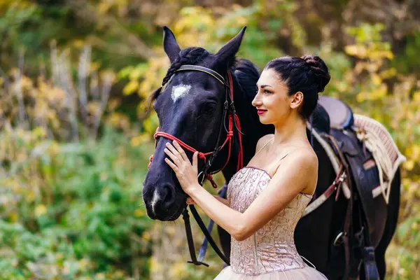 Ormanda siyah bir atı olan güzel bir balerin.