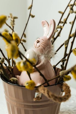 Paskalya yumurtası ve pembe arka planda söğüt dallı bir tavşan. Paskalya tavşanı. tatil konsepti. Boşluğu kopyala.