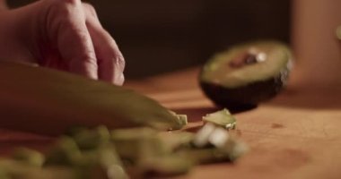 Evde sağlıklı öğle yemeği pişirirken ketojenik salata için olgun avokado kesen kimliği belirsiz bir kadının el kamerası görüntüsü.