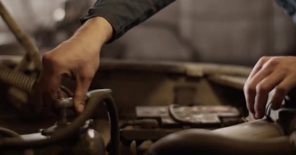 ガレージで壊れた車を修理しながら エンジンからネジを削除するためにスパナを使用して認識できない男のハンドヘルドショット — ストック動画