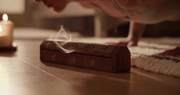自宅で床にヨガを行う女性の近くに芳香の煙を発する焼香と木製の箱の閉鎖ハンドヘルドショット — ストック動画