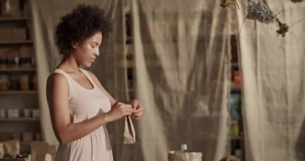 在生态商店工作的网上客户包装定单时 带有机产品的非洲裔女性卷发纸袋 — 图库视频影像