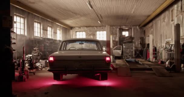 昼間に日光ガレージに駐車輝くテールライトとレトロセダン車の手持ち撮影 — ストック動画