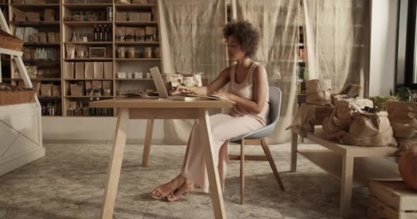 Ręczne Ujęcie Młodej Etnicznej Kobiety Siedzącej Przy Drewnianym Biurku Netbookiem — Wideo stockowe