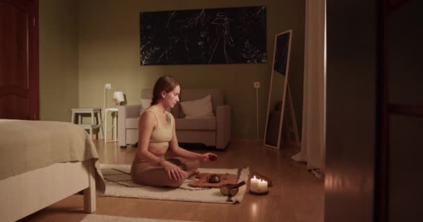 在早上的瑜伽课上 放松女性穿着活动服 盘腿坐在地板上 一边喝着新鲜的茶 一边沉思着 — 图库视频影像