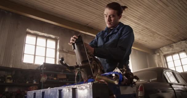 ガレージの作業台のシリンダーヘッドカバーから汚れを拭くために布を使用して均一な男性の機械工のビュー — ストック動画