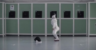 Beyaz üniformalı ve tesettürlü tanınmayan Müslüman bayan sporcunun spor salonundaki eskrim eğitimi sırasında folyoyla saldırıp hedefi vuruşunun el kamerası görüntüsü.