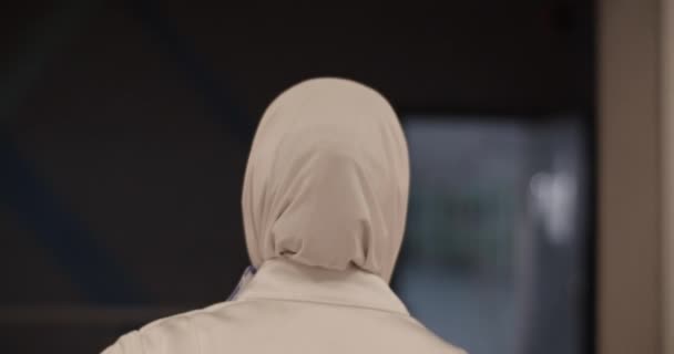 Śledzenie Ujęcia Anonimowych Muzułmańskich Sportowców Białym Hidżabie Spacerujących Ciemnym Korytarzu — Wideo stockowe