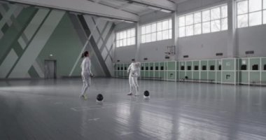 Geniş spor salonunda eskrim antrenmanına hazırlanırken folyo bükme ve kıvrımlı vücudu olan Müslüman sporcunun el kamerasıyla çekilmiş fotoğrafı.