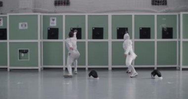 Geniş spor salonundaki eskrim eğitimi sırasında hedefleri folyoyla aynı anda vuran anonim sporcu kadınların el kamerası görüntüleri.