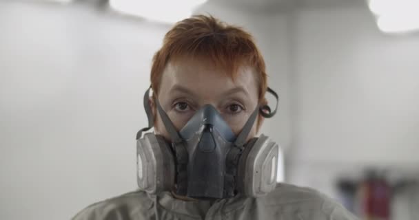 修车厂灯火通明的车间里 戴着呼吸机看着相机的生姜女工匠 — 图库视频影像