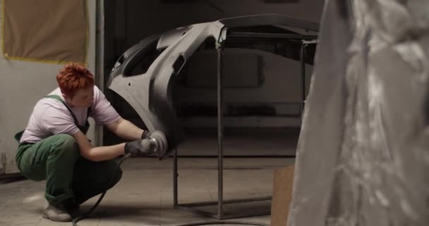 손으로 손잡이 수리공 이비치는 차고에서 일하는 자동차 위에서 사포질 기계를 — 비디오