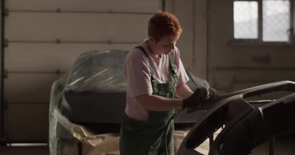 차고에서 일하는 자동차 범퍼에서 페인트를 제거하기 사포질 기계를 사용하여 머리를 — 비디오
