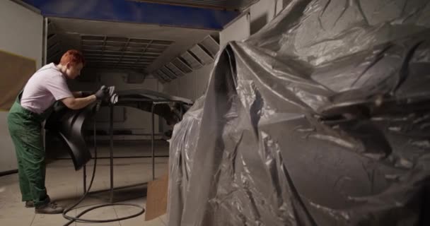 대낮에 차고에서 일하는 필름으로 뒤덮인 근처의 범퍼에 사포질 기계를 사용하여 — 비디오