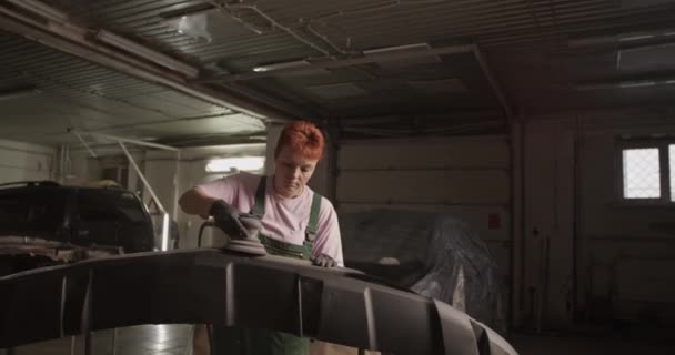 Ręczne Ujęcie Imbirowego Mechanika Jednolitym Szlifowaniu Zderzaka Stojaku Pobliżu Samochodu — Wideo stockowe